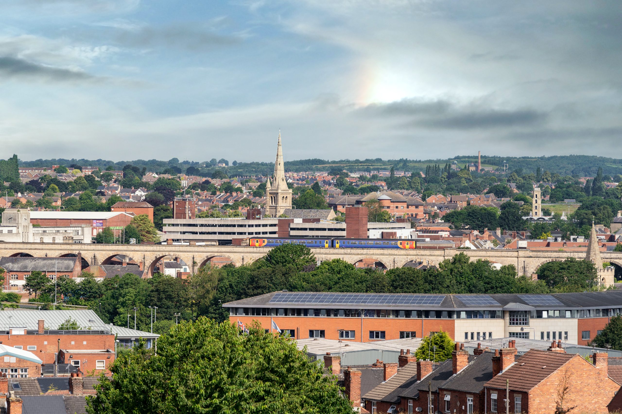 Panoramic Market town of Mansfield with St Marys and St John Church, Pleasely Pit and Fire Station tower in view as train crossing viaducts from an arial view of the urban landscape